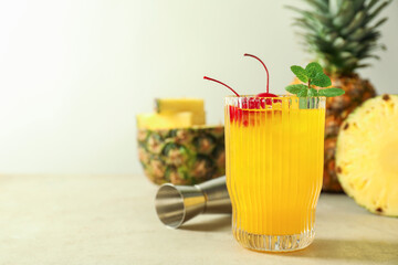 Tasty pineapple cocktail with mint and cherry in glass served on light table, space for text