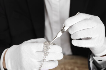 Appraiser with tweezers evaluating luxury necklace, closeup