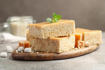Delicious puffed rice bars, candies and mint on gray textured table, closeup