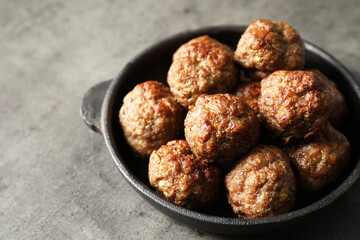 Tasty meatballs in baking dish on grey table, closeup. Space for text