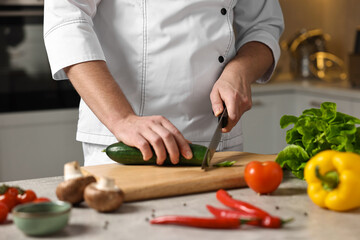 Professional chef cutting zucchini at table in kitchen, closeup