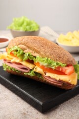 Delicious baguette sandwich with ham on grey table, closeup