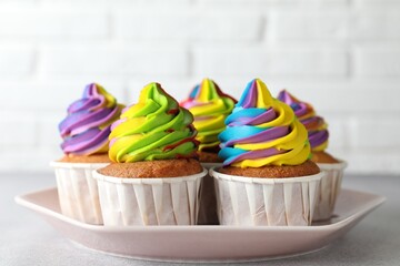 Tasty cupcakes with colorful cream on light grey table, closeup