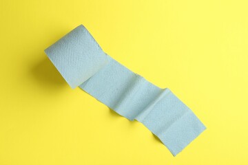Light blue toilet paper roll on yellow background, top view