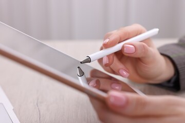 Electronic signature. Woman using stylus and tablet at wooden table indoors, closeup