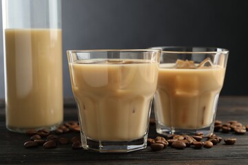 Coffee cream liqueur in glasses and beans on wooden table, closeup