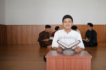 Fototapeta premium Portrait Of Young Muslim Boy Smiling And Sitting With Qur'an At The Mosque