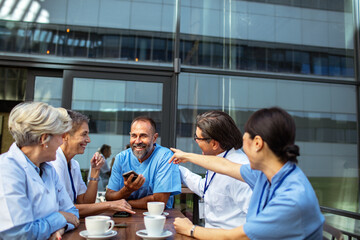 Group of diverse doctors laughing on coffee break outdoors