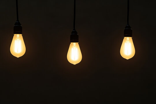 Three light bulbs hanging from the ceiling, all lit up - Powered by Adobe