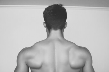 A man with a muscular back and a shaved head