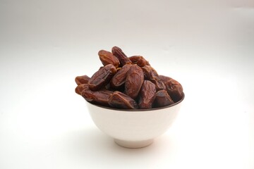 Dried dates fruits in ceramic bowl isolated on white background.