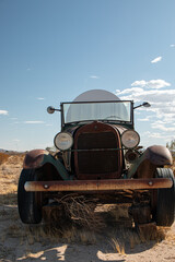 Front view of an antique Model A truck hauling a large tank in the desert.