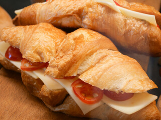 Fresh croissants filled with cheese and tomatoes on a wooden table