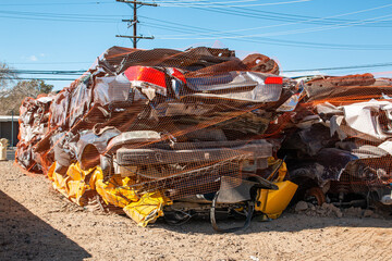 Compact cars smashed by the crusher at a salvage yard and stacked ready for shipment for recycling.