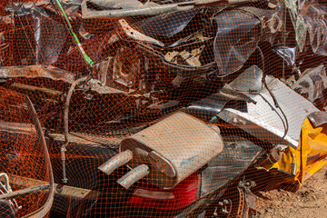 Close up of cars smashed by a crusher and wrapped in orange netting for shipment for recycling.