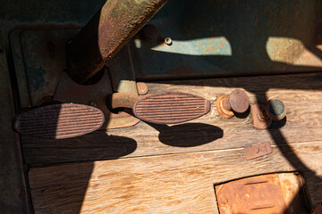 Foot pedals and controls on the floorboard of an antique Model T style truck.