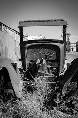 Front view of the remains of an antique Model T flatbed truck in black and white.