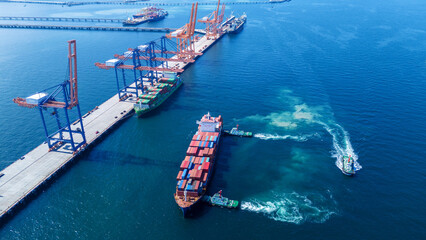 Tug boat pulling Cargo container ship go to international yard port. technology freight shipping...