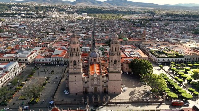 Cathedral and panoramic view of the city with mountains in the background during the afternoon. Drone camera approaches descending on the church facade