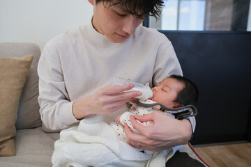 哺乳瓶で新生児にミルクを飲ませる父親