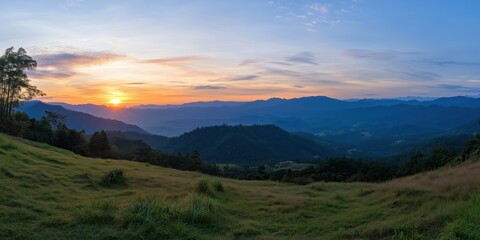 A breathtaking sunset casts golden and orange hues across a vast mountain landscape, highlighting the serene beauty of nature in a tranquil and picturesque setting.