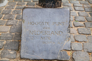 A close-up view of a concrete border marker indicating the highest point in the Netherlands, highlighting the elevation.