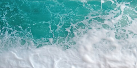 Fototapeta premium An overhead shot captures the beautiful contrast of turquoise ocean waves cresting and crashing against a serene sandy beach, showcasing nature's artistry and power.
