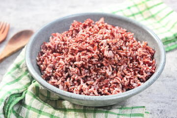 a bowl of cooked brown rice on the table with a spoon and fork