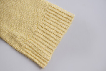 Texture of sleeve on yellow knitted sweater fabric. Flat lay style, close-up.