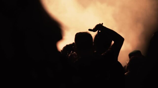Toma en c&aacute;mara lenta y a contraluz de personas bailando en un festival de m&uacute;sica