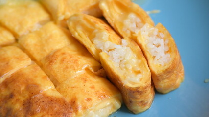 roll omelette stuffed with chesse and rice on blue plate, delicious food in the morning
