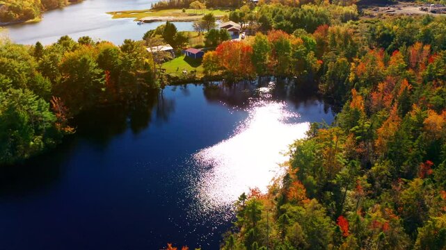 Aerial drone shot over the coastline of Oak Island, Nova Scotia, Canada.
High view of the sea, autumn colorful trees foliage. Picturesque landscape. Fall vibrant colors.