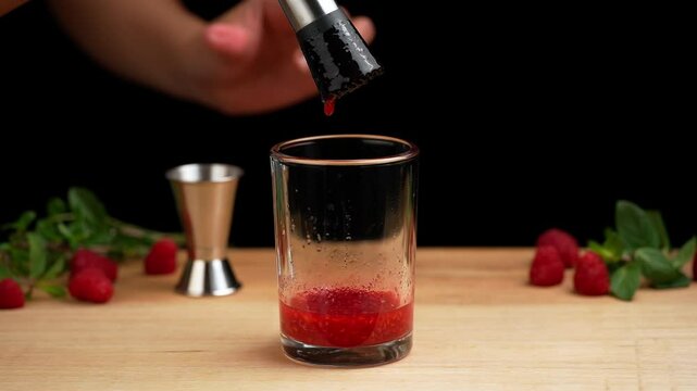 Raspberry mojito, mashing raspberries with a muddler to prepare a mojito