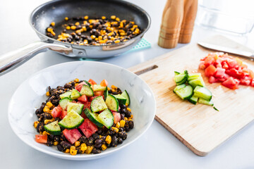 bean corn tomato and cucmber salad being made on kitchen bench