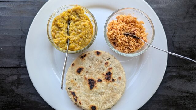 Traditional Sri Lankan breakfast cuisine of lentil dahl curry, pol sambol, and coconut roti, top down view served on white plate