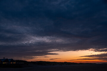 A stunningly beautiful view of a pristine beach at sunset, featuring vibrant colors and moody clouds all around it