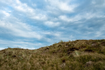 A charming, peaceful scene beautifully showcasing gentle grassy hills silhouetted against a cloudy sky