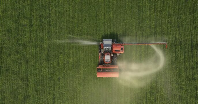 Overhead view of a tractor spraying herbicide in a field with crops , equipment, farming