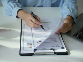Young businesswoman holds a resume and evaluates it. Views the personal history of job applicants....