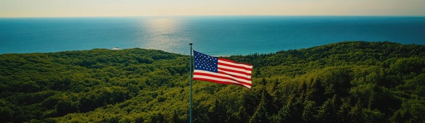 A stunning aerial view of the American flag waving in front of Lake Michigan, with lush green forests and blue waters stretching into the distance.