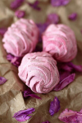 Deliciously soft pink marshmallows crafted at home on rustic brown paper served dry purple flowers.