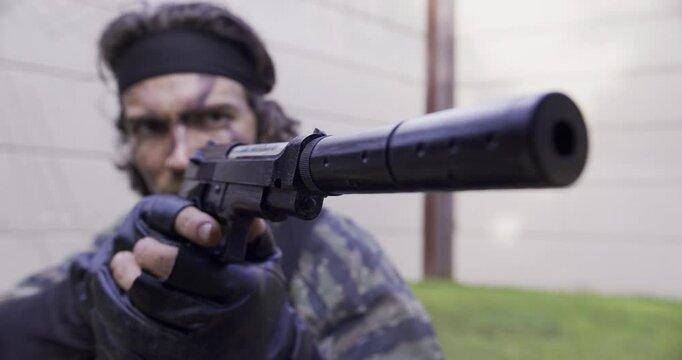 Epic shot of soldier aiming handgun with silencer - close up