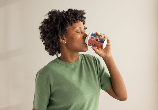 Black woman sips from a disposable takeaway paper cup with a lid.  PSD template mockup ready for your Design