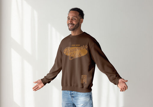 A black man stands confidently in a cozy sweater, looking away, radiating relaxed style and modern fashion sense.