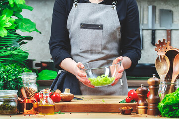 Chef holds bowl with chopped celery prepare salad. Cozy kitchen with wooden table, kitchenware,...