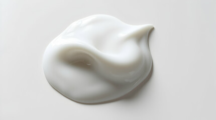 A close-up shot of a dollop of white cream on a light, neutral surface, showcasing its smooth texture and glossy appearance.