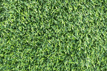 close-up of a lush, green artificial turf. The synthetic blades of grass are perfectly aligned and create a uniform