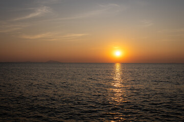 Obraz premium serene sunset view over the ocean, with the sun casting a warm golden reflection