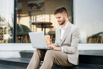 Fototapeta premium Successful businessman works outdoors near the office holds a tablet