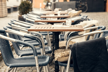 A charming outdoor cafe with empty tables and woven chairs on a cobblestone street in a European city. A perfect setting for travel, hospitality, and lifestyle imagery